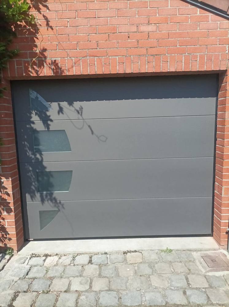 Porte de garage sectionnelle gris anthracite avec hublots, façade en briques